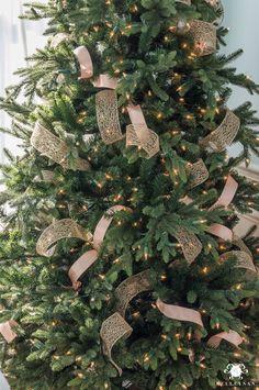 a decorated christmas tree with pink ribbon and lights