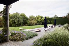 an outdoor patio with tables and umbrellas surrounded by flowers, shrubs, and trees