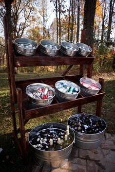 an outdoor picnic area with metal buckets and cans on a wooden stand in the woods