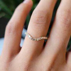 a woman's hand with a gold band and diamond ring on her left hand