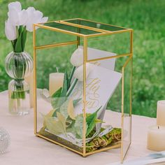 a table with candles, flowers and cards in a glass box on top of it