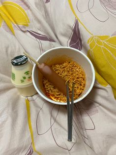 a bowl of noodles and a spoon on a bed