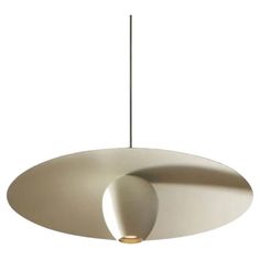 a large white light hanging from a ceiling fixture with an oval shape on the top