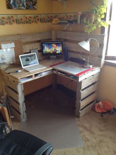 a desk made out of pallet wood with a laptop on it