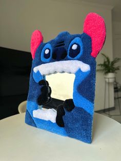 a blue and red stuffed animal sitting on top of a white table next to a mirror