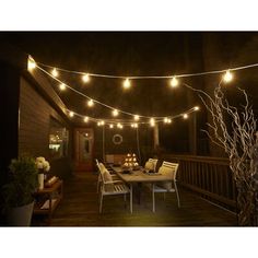 an outdoor patio with string lights strung over the table and chairs on the deck at night