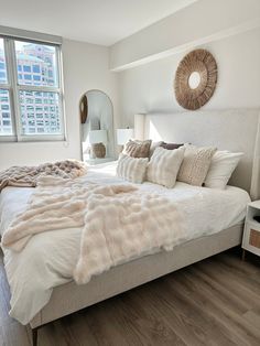 a large bed sitting in a bedroom on top of a hard wood floor next to a window