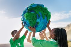 two children holding up a large green and blue earth