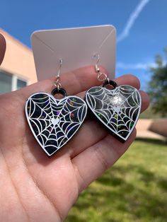 Each pair of black spiderweb heart earrings are handmade to order, therefore no two pairs are identical! However, I try to get as close as possible :) Made with sterling silver plated fishhook earrings (clear rubber backing included). Hypoallergenic & nickel-free. Each spiderweb heart is made with epoxy resin, black liquid pigment, and chunky holographic glitter ✨  Perfect for Halloween, as a gift for a friend, etc. Color may vary slightly. Thanks for visiting my shop! 🕷 🌈 Black Themed Jewelry For Valentine's Day, Themed Black Jewelry For Valentine's Day, Black Heart Earrings For Pierced Ears As Gift, Black Heart Earrings As A Gift, Black Heart Dangle Earrings For Gift, Handmade Spooky Black Earrings, Gothic Black Heart-shaped Earrings, Spooky Black Jewelry Gift, Handmade Black Dangle Heart Earrings