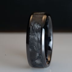 a black and white wedding ring with an intricate design on it's center, sitting on a table