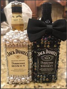 two bottles of jack daniels with pearls in the bottom and a bow tie on top