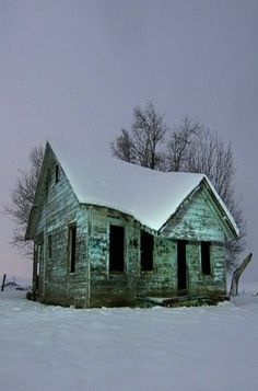 an old run down house in the middle of winter with snow on it's roof