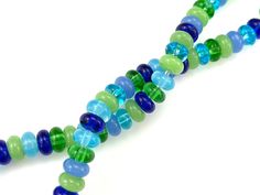 a multi - colored beaded necklace is displayed on a white surface with blue and green beads