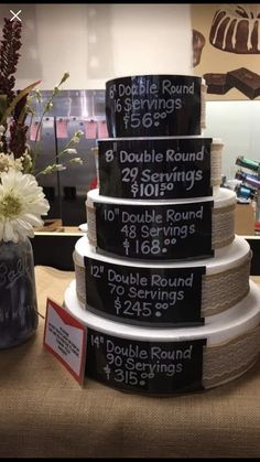 a table topped with three tiered cakes covered in black and white labels next to a vase filled with flowers