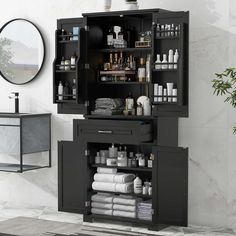 a black cabinet with lots of bottles and towels in it next to a mirror on the wall