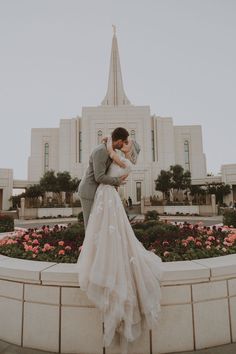 a bride and groom kiss in front of the mormon temple during their wedding photo session