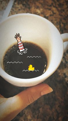 a hand holding a coffee cup with a rubber duck floating in the water on it