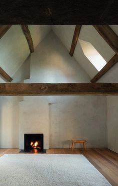 an empty room with a fire place in the center and wooden beams on the ceiling