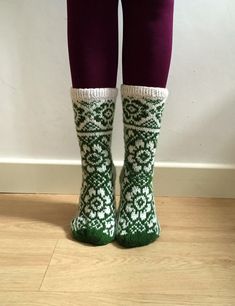 the legs of a person wearing green and white knitted socks with snowflakes on them