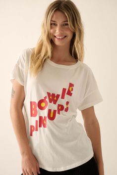 David Bowie Pinups Garment-Wash Graphic Tee - ShopPromesa Cotton Pop Culture Tops For Summer, Summer Cotton Pop Culture Tops, Band Merch Crew Neck Top With Slogan, Pop Culture Graphic Print Tops In Relaxed Fit, Relaxed Fit Graphic Print Tops Pop Culture, Relaxed Fit Graphic Print Tops For Pop Culture, Pop Culture Slogan Tops With Relaxed Fit, Band Merch Cotton Top With Front Print, Band Merch Slogan Tops For Summer