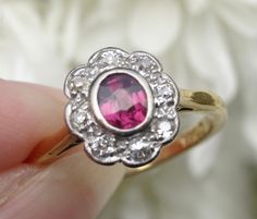 Free shipping and complementary resizing*! Exceptionally pretty and classic, this antique ruby cluster ring is as timeless as the day it was handmade with love, by an artisan, in England in the early 1900's. This gorgeous ruby is .57 carat and is surrounded by beautiful twinkling high quality diamonds that total .32 carat. The ruby varies in shade from a purple/pink/red in bright sunshine, to a cherry red at night. The diamonds add that perfect little bit of sparkle and the decorative basket is Antique Style Rings, Bright Sunshine, Decorative Basket, Ruby Diamond, Diamond Cluster Ring, Diamond Cluster, Cherry Red, Cluster Ring, Quality Diamonds