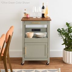 a kitchen cart with plates and wine bottles on it next to a potted plant