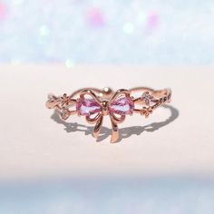 This ring will get you feeling extra pretty in pink! Wrap yourself up in a bow and celebrate the greatest present there is--you! Featuring a delicate intertwining band and dazzling embellishments, all leading to a perfect pink ribbon. This piece will make you feel like the ultimate gift! 18k gold plated, 18k rose gold Pink Ribbon Jewelry As Gift, Pink Ribbon Jewelry Gift, Pink Ribbon Jewelry For Gifts, Pink Party Jewelry With Butterfly Knot Detail, Pink Party Jewelry With Butterfly Knot, Pink Ribbon Wedding Jewelry, Pink Bow Jewelry Gift, Feminine Party Jewelry With Pink Bow, Pink Feminine Jewelry With Bow