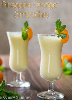 two glasses filled with orange smoothie on top of a table