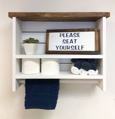 a shelf with towels, toilet paper and a sign on it that says please seat yourself