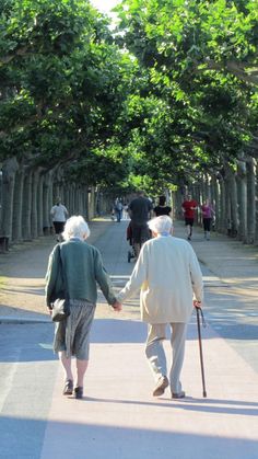 an older couple walking down the street holding hands