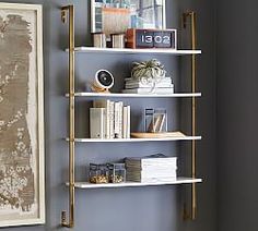 a white shelf with books and pictures on it next to a wall mounted art piece