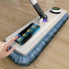 a person using a mop to clean a wooden floor with a cell phone in it