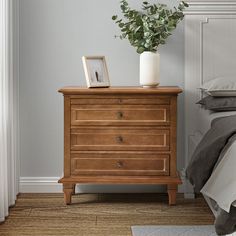 a wooden dresser sitting next to a bed with a plant on it's top