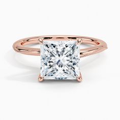 a princess cut diamond ring with pave set diamonds on the band and shoulders in 18k rose gold