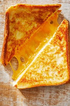 grilled cheese sandwich with melted cheese on wooden table top, cut in half to look like two triangles