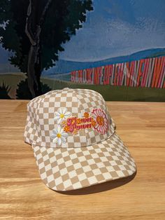 Upgrade your spring and summer style with our Flower Power Checked Cap. This white and tan checkered baseball cap features floral and heart patches for a playful yet stylish look. Get ready to rock your flower power vibes with this quirky and fun accessory! A Cactus Jane Original, made in house at our Laguna Beach store front Vintage Adjustable Baseball Cap For Spring, Cream Snapback Trucker Hat For Spring, Cute Spring Trucker Hat With Curved Brim, Retro White Trucker Hat For Spring, Cute Spring Hat With Curved Bill, Cute Curved Bill Hat For Spring, Trendy Adjustable Hats For Picnics, Spring Adjustable Baseball Cap With Curved Visor, Trendy Cream Trucker Hat With Curved Brim