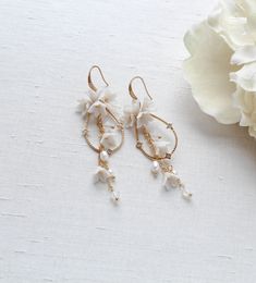 Our Irena teardrop Hoop Floral earrings for Bride are designed to be show stopping dangle hoops that will have everyone asking "where did you get those?!" Crafted with off white flower clusters & dangling freshwater pearls and white opal Austrian crystal beads, these earrings are perfect for casual or formal wear. - Handcrafted with genuine Austrian crystals- Created in my studio in PA- White opal crystals- Freshwater pearls- Polymer clay flowers- Yellow gold finish.- Earrings measure 3.25 inches x 1 inch- Handcrafted in the US.- Nickel free and hypoallergenic- PLEASE ALLOW APPROX 10 BUSINESS DAYS FOR COMPLETION BEFORE SHIPPING.This is an original design by © Treasures by Agnes Bridal Backdrops, Bridal Backdrop Necklace, Earrings For Bride, Gold Bridal Hair Comb, Backdrops Necklace, Crystal Bridal Earrings, Cubic Zirconia Bracelet, Flowers Yellow, Rose Gold Bridal