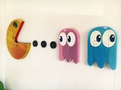 three different colored wall hooks with eyes and mouths hanging on the wall next to each other