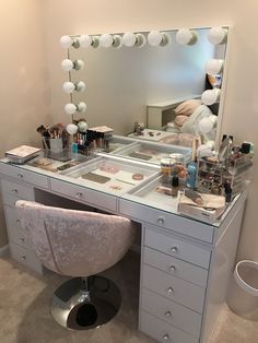 a vanity with a mirror, stool and various makeup products on it in a room