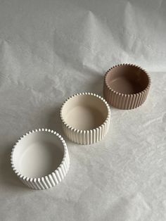 three empty dishes sitting on top of a white tablecloth covered floor next to each other