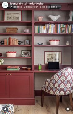 a red bookcase with many books on it and a chair in front of it