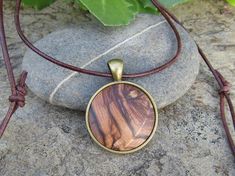 "Lovely bronze pendant medallion with a handmade cabochon Ø 25 mm - 0.98 inches in fine olive wood with a 75 cm - 29.5 inches long bronze plated chain or an adjustable leather cord 1 meter ( 39.37 \" ) naturally the grain of the olive wood can vary from item to item , but in any case you will get a pendant with an olive wood cabochon with beautiful grain handcrafted by us in Portugal the olive wood is finely sanded and oiled with olive oil" Spiritual Brown Oval Pendant Jewelry, Bohemian Natural Wood Necklaces As Gift, Bohemian Natural Wood Necklace As Gift, Brown Engraved Brass Jewelry, Brown Necklace With Large Round Pendant, Handmade Natural Wood Pendant Jewelry, Unique Brown Round Pendant Necklace, Unique Brown Round Pendant Jewelry, Brown Necklace With Large Pendant For Gift