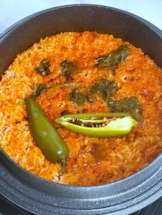 a pan filled with rice and vegetables on top of a stovetop oven next to a green pepper