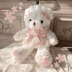 a white teddy bear sitting on top of a bed next to a dresser with pink flowers