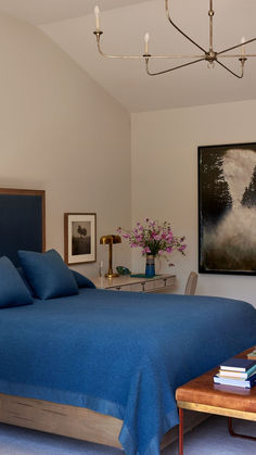 a bedroom with blue bedding and artwork on the wall