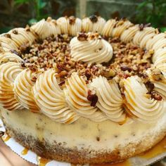 a cake with white frosting and pecans on top is sitting on a plate