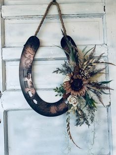 a wreath hanging on the side of a door with dried flowers and leaves attached to it