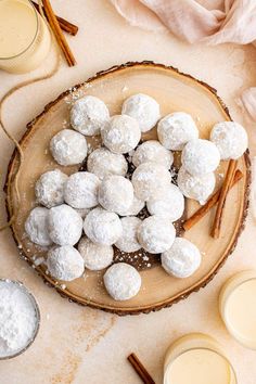 a plate filled with snowball cookies and cinnamon sticks