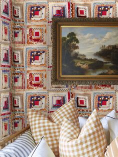 a painting hanging on the wall above a bed covered in pillows and throw pillows with checkered patterns