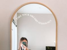 a woman taking a selfie in front of a mirror with the words take your dreams seriously written on it